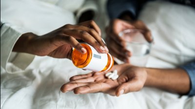 Medication being handed from bottle to patients hand
