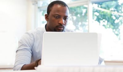 man sits in front of white laptop