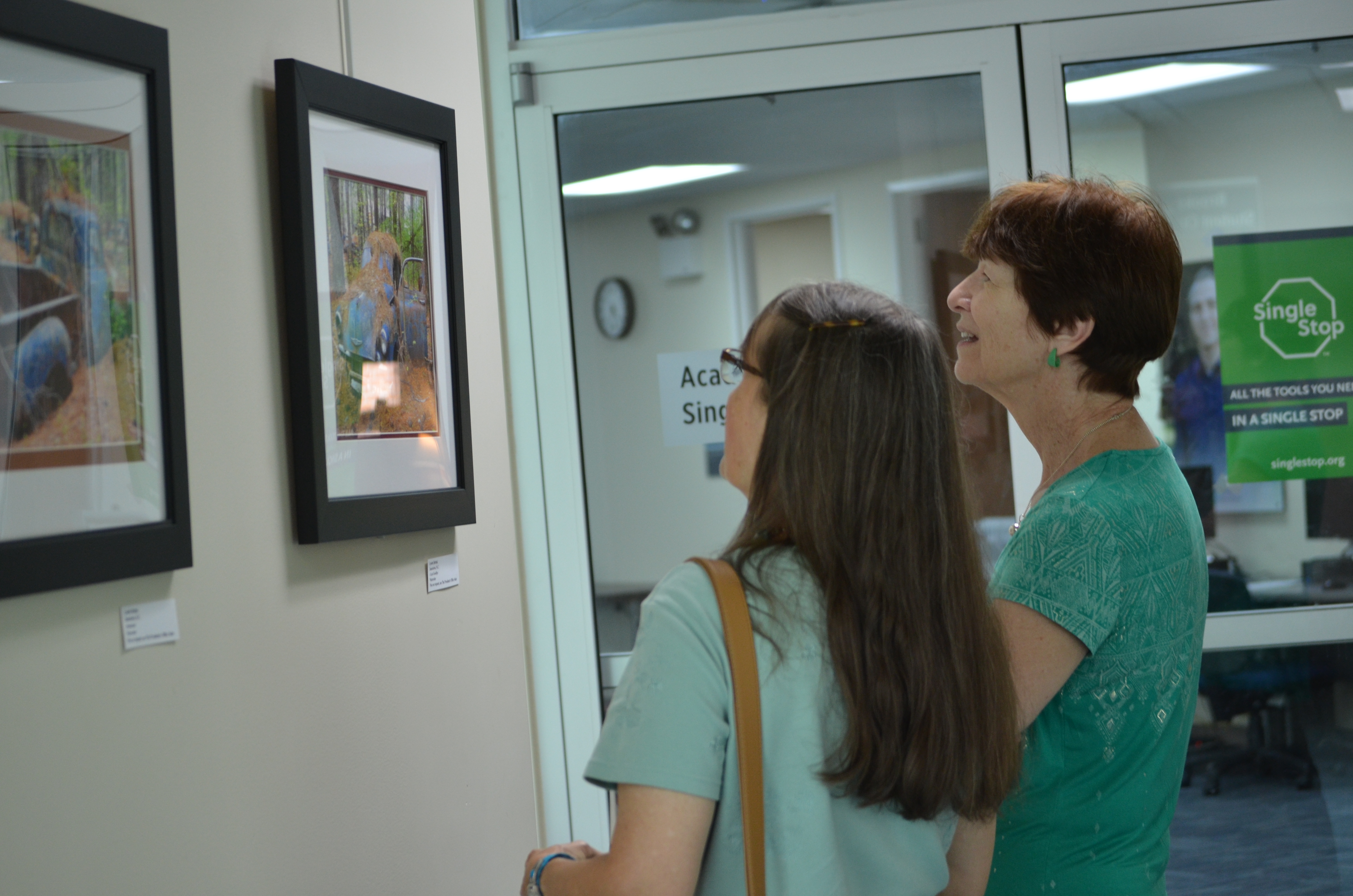Two women look at two photography art pieces. 