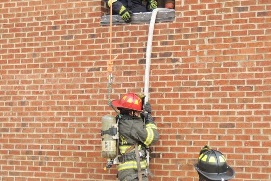 Firefighter repelling down brick building
