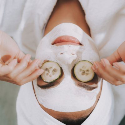 individual with cosmetic mask on face and cucumbers on eyes