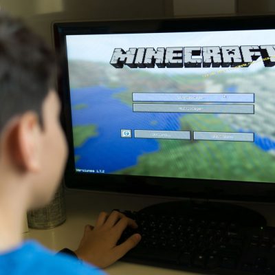 Student in front of computer screen with Minecraft game on screen