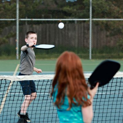 young children play pickle-ball outside