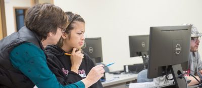Instructor helps student at computer