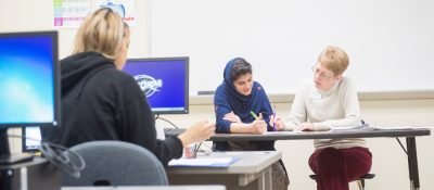 Instructor helps student at desk