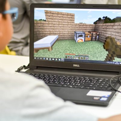 student playing Minecraft on open laptop