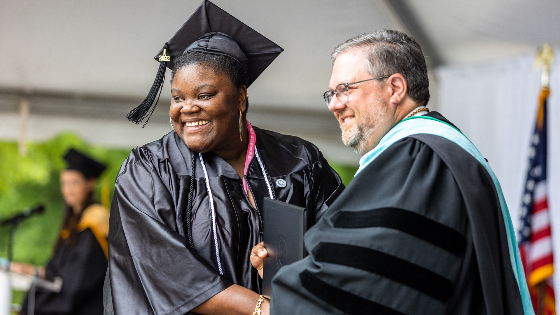 Graduate in cap and gown shakes Dr. Hartness' hand has they receive diploma