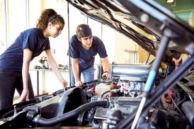 Two automotive students look under the hood of car