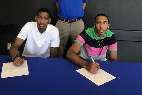 Two basketball players signing papers