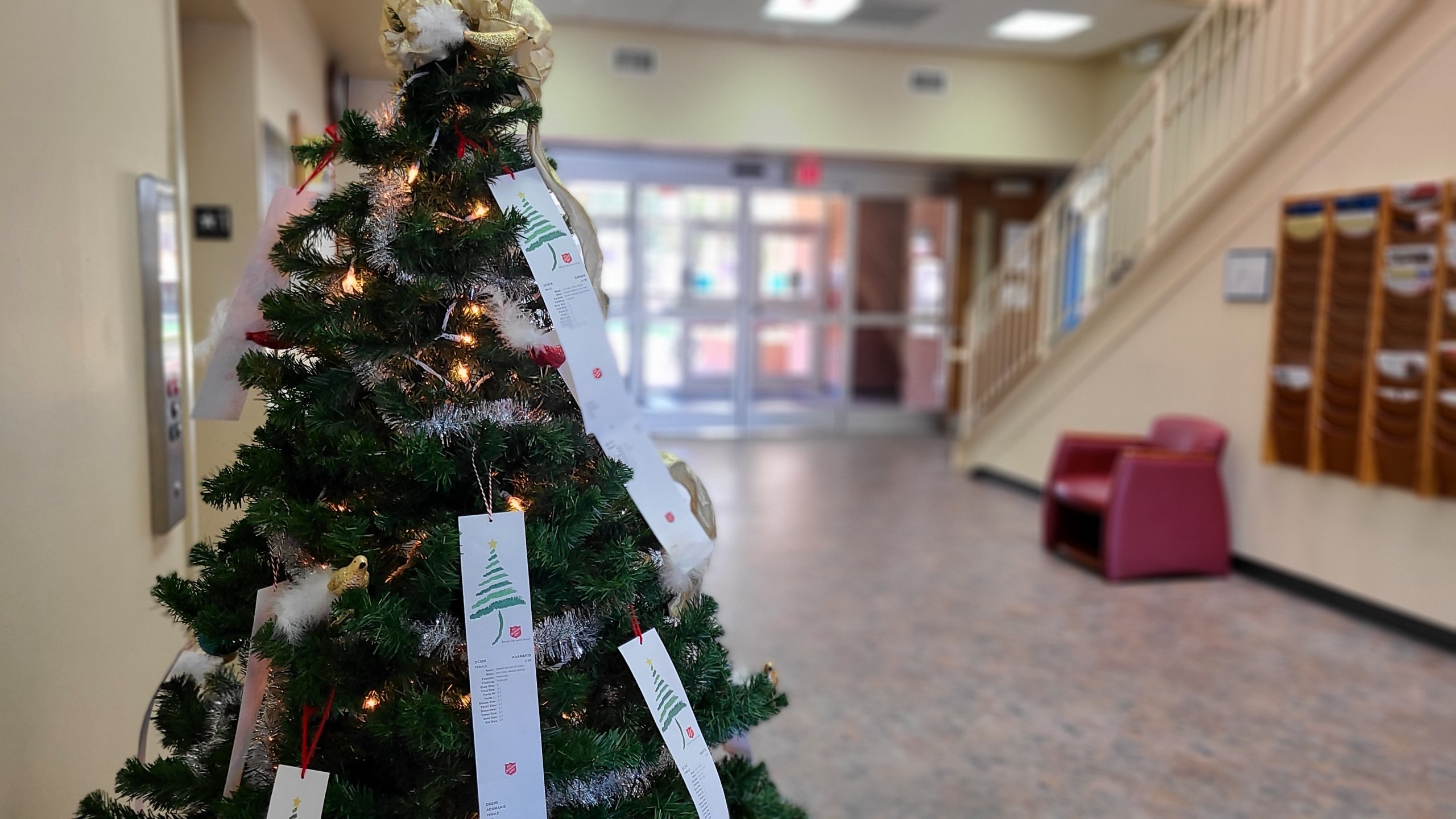 Christmas tree in common area with Angel tree names hanging from it