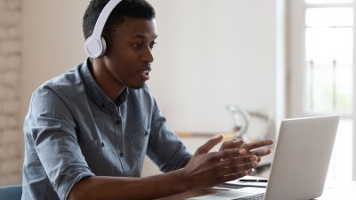 teenage boy with white headphones in front of laptop