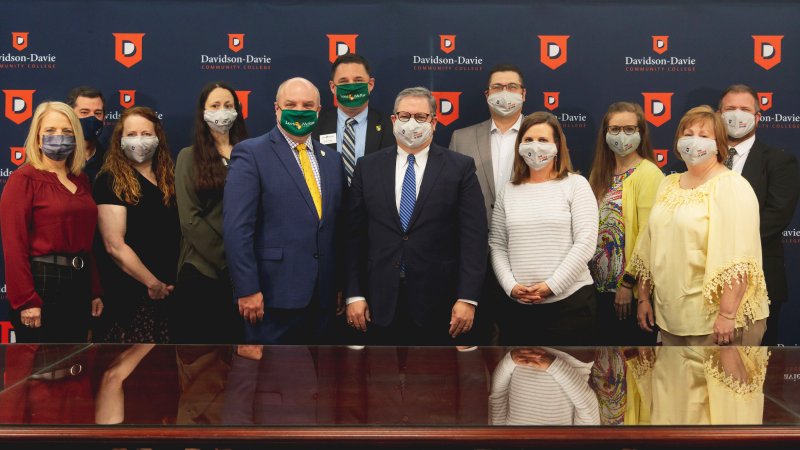 Group Photo of College Leadership wearing masks in front of Davidson-Davie backdrop