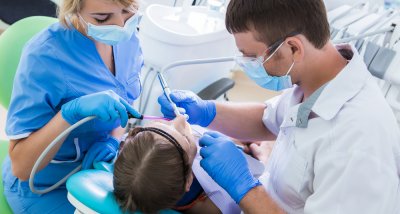 two dental healthcare providers using instruments in patients mouth