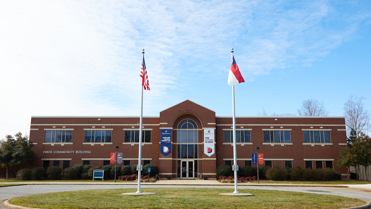 Davie Campus Community Building with flag poles in front