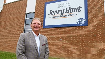 Todd Hunt stands in front of Jerry Hunt Supercenter banner on Brinkley Building External wall
