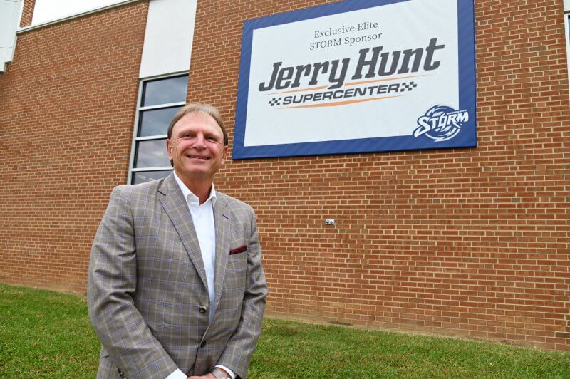 Todd Hunt stands in front of Jerry Hunt Supercenter banner on Brinkley Building External wall