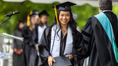 Graduate walks across stage holding diploma