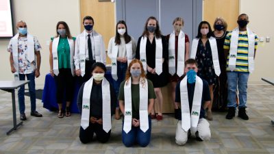 Group of masked studnets with white graduation stoles