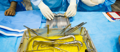 Surgical Instruments being touched by hands wearing latex gloves
