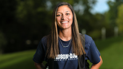 Outdoor photo of smiling student wearing a navy Davidson-Davie t-shirt.