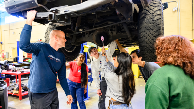 Automotive Students and Instructor look underneath car
