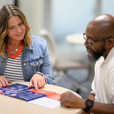 A woman and man at a table discussing a brochure.