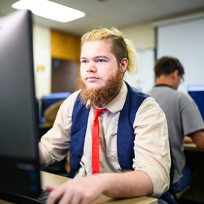 A person working on a computer in a classroom.