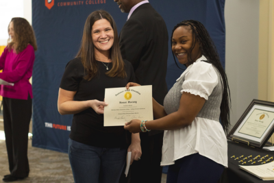 A woman receives a National Adult Education Honor Society certificate.