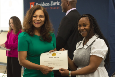 A woman receives a National Adult Education Honor Society certificate.