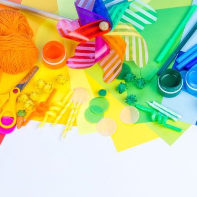 Assorted colorful craft supplies on vibrant papers.