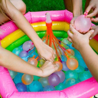 Children playing with colorful water balloons in a small inflatable pool.